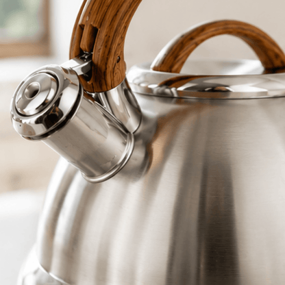 Stainless steel kettle with wooden handles on a blurred background